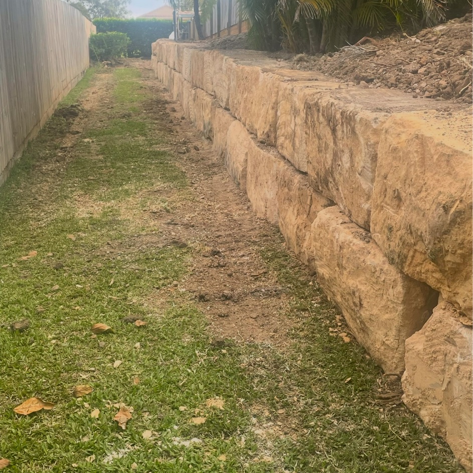 Large sandstone block retaining wall supporting a commercial boundary
