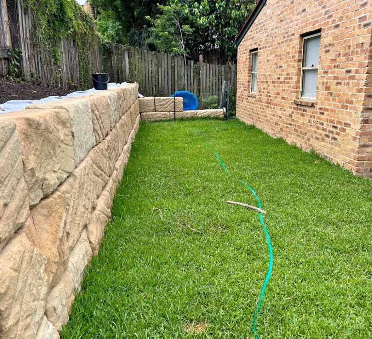 Sandstone block retaining wall beside fresh turf
